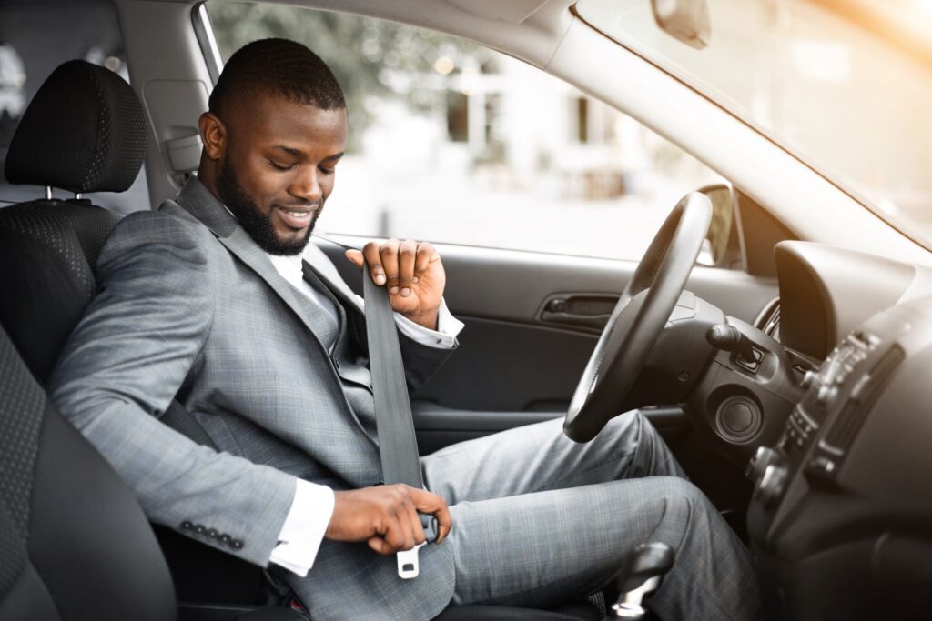 A man wearing a suit buckles into his new car, which he leased after emerging from bankruptcy protection.