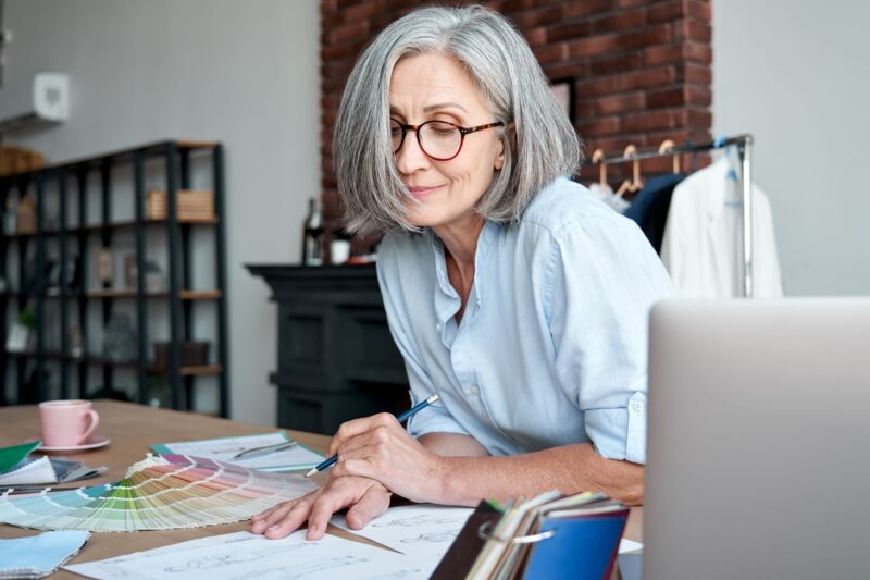 Older woman, smiling as she looks over her business papers.