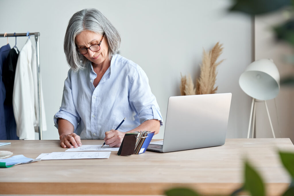 woman with gray hair writing at desk in front of laptop learning what is a single member llc