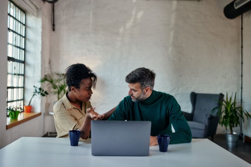 A couple sitting at the table, looking at a laptop together, as they try to get an online divorce in Missouri.