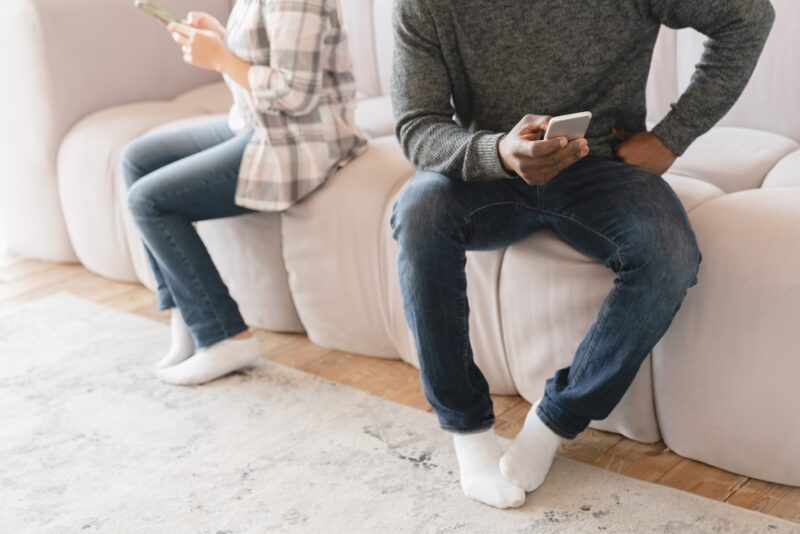 woman and man sitting on couch facing away from each other using smart phones to learn what is an online divorce